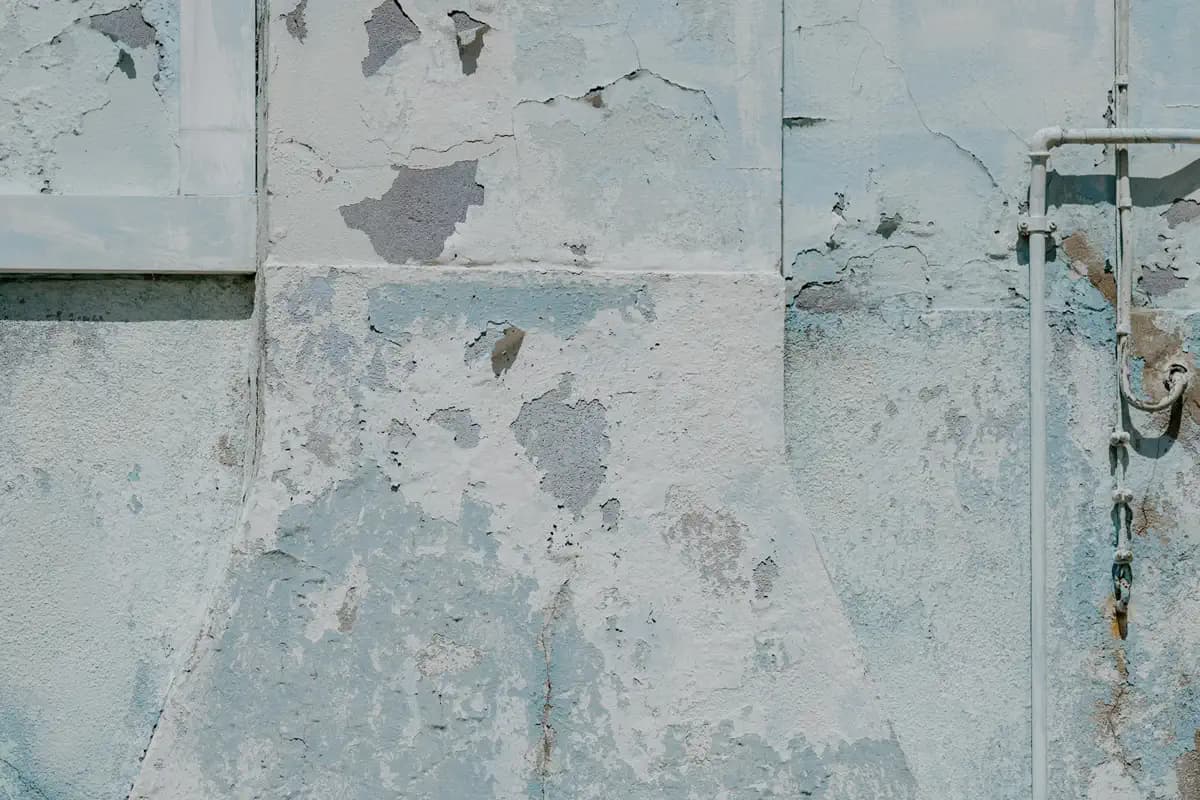 Parede com a tinta descascando em placas, com marcas de umidade