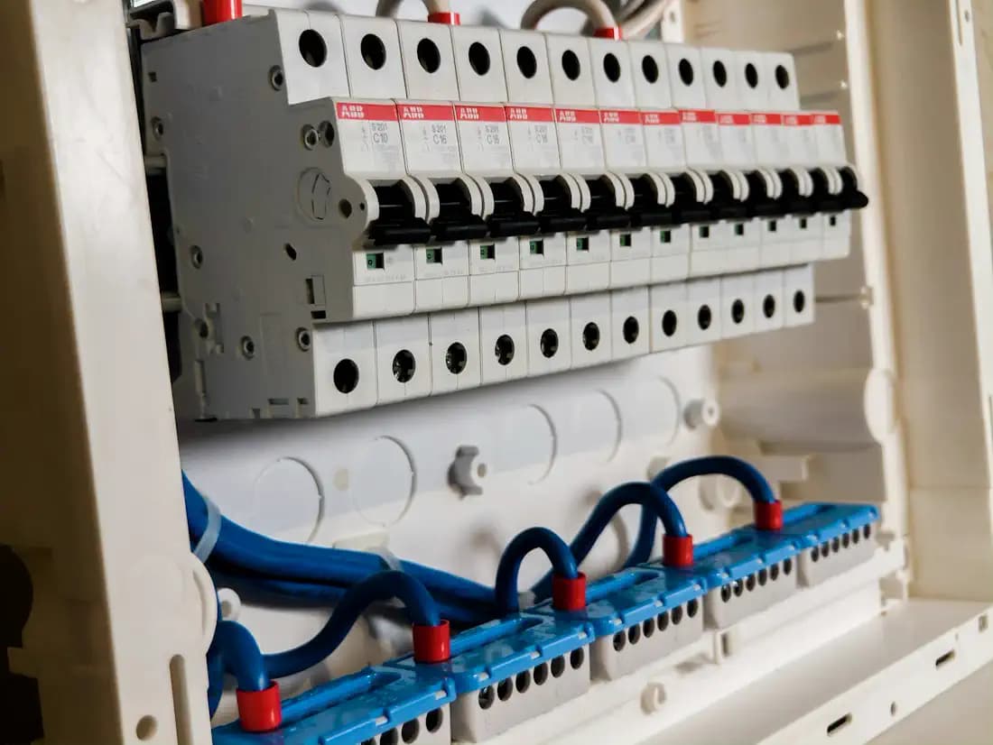 Quadro de disjuntores com fileiras de chaves brancas e fios azuis e vermelhos